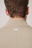Back view of a beige athleisure jacket collar with '8.9' detail and a small white tag