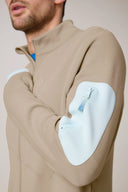 Beige athletic jacket with light blue zip pocket on sleeve, close-up on male model