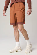 Man wearing sepia brown athletic shorts, long sleeve shirt, white socks and sneakers
