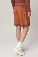 Back view of person wearing sepia brown athletic shorts with side slit, white socks, and sneakers