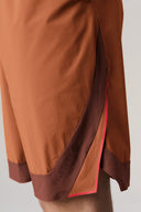 Close-up of colorblock sepia athletic shorts with side panel and red trim detail
