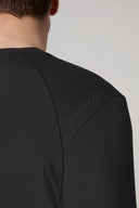 Close-up of men's charcoal active tee shoulder with subtle logo and ergonomic seam detail