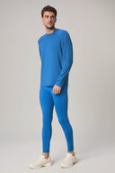 Man in cobalt blue long sleeve active tee and leggings, beige sneakers, studio background