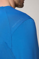 Close-up of cobalt blue athletic tee on shoulder with visible textured fabric and logo detailing