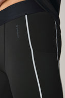 Charcoal reflective leggings with side stripes and pocket detail, close-up view.