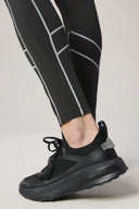 Close-up of charcoal reflective leggings with geometric stripes and black athletic shoes