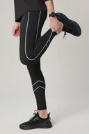 Person stretching in charcoal reflective leggings with sporty black sneakers