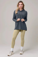 Woman wearing a granite gray long sleeve pima cotton hoodie and beige leggings