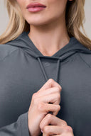 Close-up of woman wearing granite gray long sleeve Pima cotton hoodie, holding drawstrings