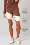 Woman wearing colorblock high-waisted athleisure leggings in sepia, white, and tan.