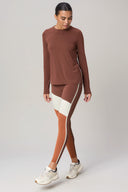 Woman wearing brown colorblock activewear leggings and matching long sleeve top