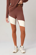 Woman wearing high-waisted colorblock leggings in brown, cream, and rust athleisure style