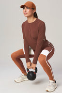 Woman in brown and white colorblock leggings and long sleeve top squatting with kettlebell