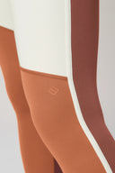 Close-up of colorblock sepia, cream, and terracotta leggings with logo detail