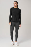 Woman wearing charcoal long sleeve activewear top and gray leggings with white sneakers