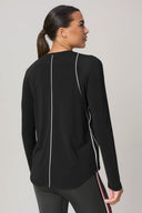 Woman wearing charcoal long sleeve athleisure sweater with white piping back view