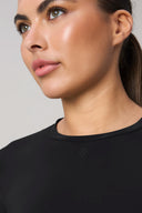 Close-up of a woman wearing a black long sleeve athleisure sweater, neutral background