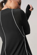 Back view of woman wearing charcoal long sleeve athletic sweater with mesh details and white piping