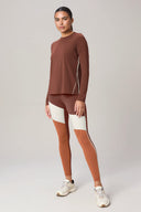 Woman wearing a brown long sleeve athleisure sweater with colorblock leggings
