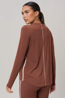 Woman in sepia long sleeve athleisure sweater with white piping, rear view