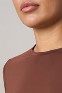 Close-up of a person wearing a sepia long sleeve activewear top with crew neckline