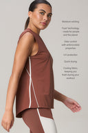 Woman wearing a sleeveless brown athletic tank and matching leggings, with side mesh panel, standing in profile. Text highlights features like moisture wicking, antimicrobial odor control, UV protection, and quick-drying fabric.