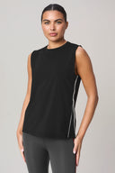 Woman wearing a sleeveless charcoal athletic top with side detail and gray leggings