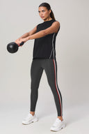 Woman in sleeveless charcoal athletic top and stripe leggings lifting kettlebell