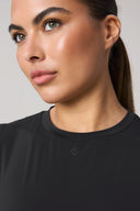 Close-up of woman wearing sleeveless charcoal athletic top, smooth skin, ponytail