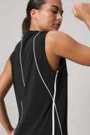 Woman wearing charcoal sleeveless athletic top with white trim and mesh back panels