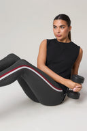 Woman in charcoal sleeveless top and stripe leggings holding dumbbell, activewear outfit