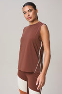 Woman wearing sleeveless brown athletic top and colorblock leggings, posing studio