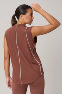 Woman wearing sleeveless sepia activewear top with mesh panels and contrast piping, back view