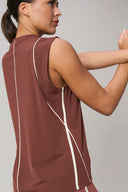 Woman stretching in sleeveless sepia activewear top with white piping and perforated panels