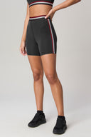 Woman wearing charcoal high-waisted bike shorts with red and white side stripes