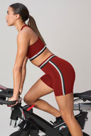 Woman in merlot red bike shorts and matching crop top riding stationary bike, activewear