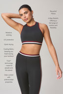 Woman modeling charcoal athletic bra and leggings with maroon trim, showcasing eco-friendly, moisture-wicking, stretch activewear.