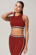 Woman wearing a merlot red sports bra and leggings with striped elastic bands, athleticwear