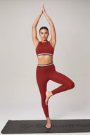 Woman in red yoga outfit doing tree pose on a yoga mat, activewear for fitness and yoga
