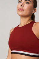 Woman wearing a merlot red high-neck sports bra with striped elastic band