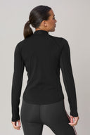 Woman wearing a charcoal athletic jacket with mesh panels, viewed from the back