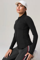 Woman wearing black zip-up athleisure jacket with mesh panels, white cap, and striped leggings