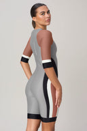 Woman wearing a fitted, colorblock short-sleeve athletic bodysuit in gray, brown, black, and white.