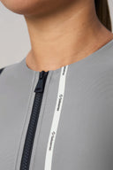 Close-up of a gray athletic rashguard with black zipper and white logo trim detail