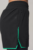 Charcoal athletic shorts with green trim, side zipper pocket, and elastic waistband