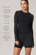 Woman wearing charcoal long sleeve active tee and black athletic shorts, moisture-wicking, UV protection, odor control, 4-way stretch.