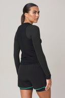 Woman in charcoal long sleeve active tee and black athletic shorts with green trim