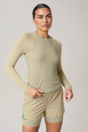 Woman wearing pale olive long sleeve active tee and matching athletic shorts