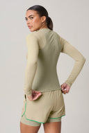 Woman wearing pale olive long-sleeve active tee and matching shorts, back view