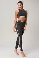 Woman wearing charcoal leggings and matching crop top with red and white striped trim